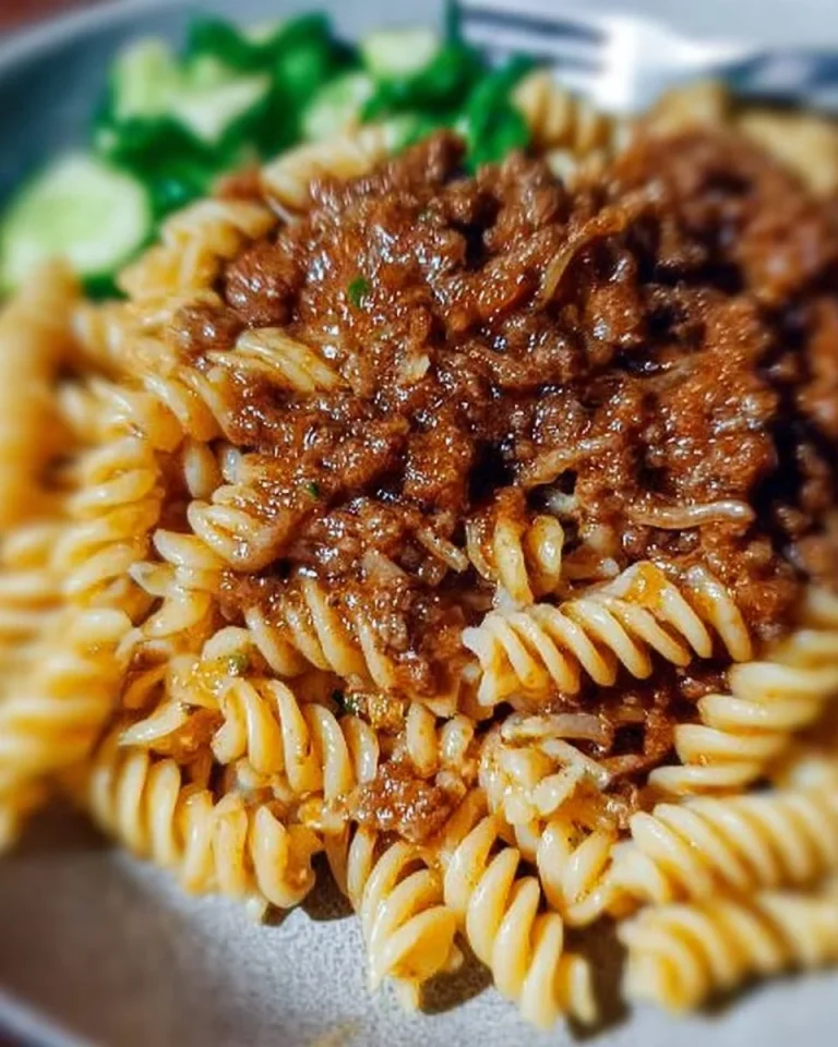 Hackfleischsoße mit Nudeln und frischem Gurkensalat auf dem Teller