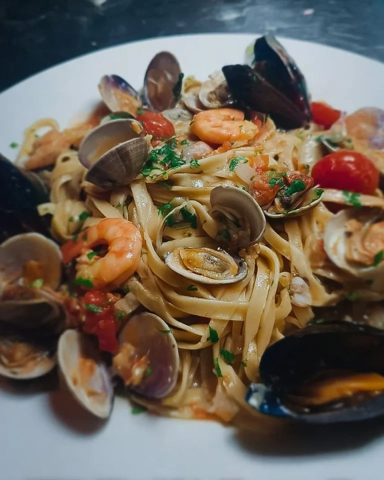 Fettucce mit Kirschtomaten, Garnelen, Muscheln und Venusmuscheln auf einem Teller