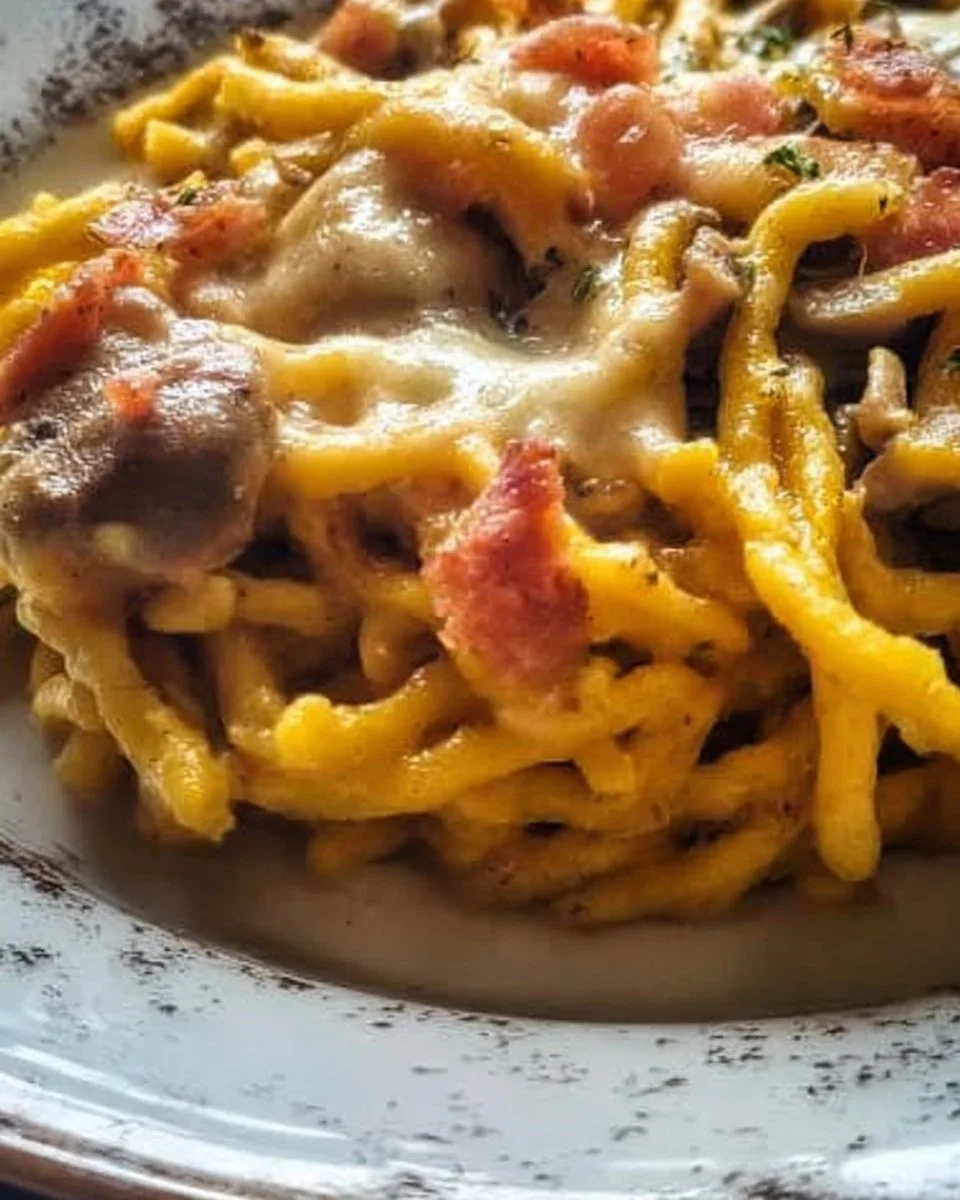 Trofie mit Safran, Pilzen, Provola und Speck auf einem Teller