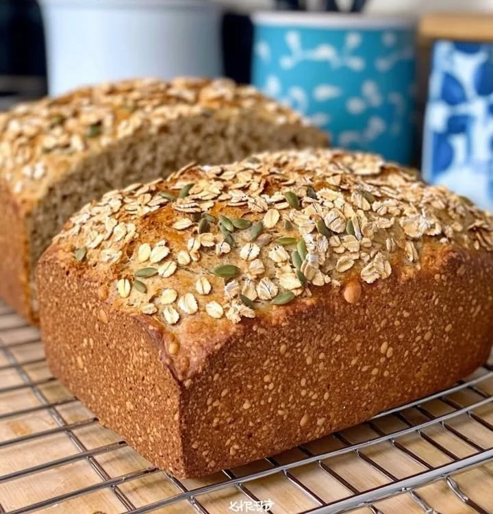 Scheiben von frisch gebackenem Haferflocken-Kürbiskern-Brot auf einem Holzbrett
