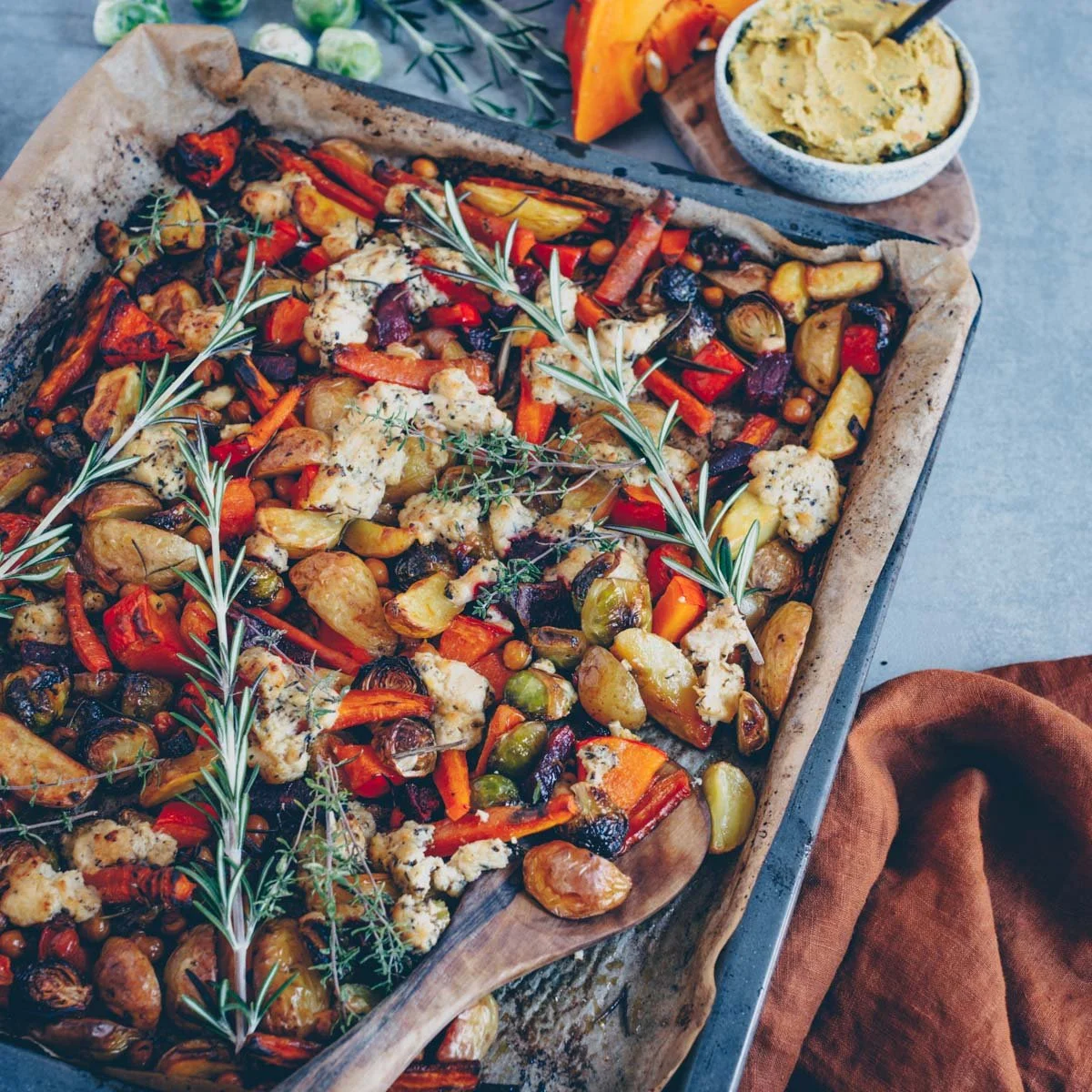 Herbstliches Ofengemüse mit veganem Feta auf einem Blech angerichtet.