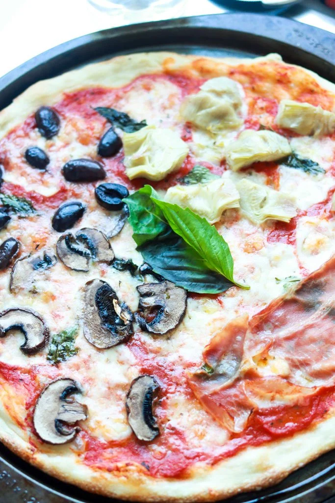 Pizza Quattro Stagioni mit unterschiedlichen Belägen auf einem Teller