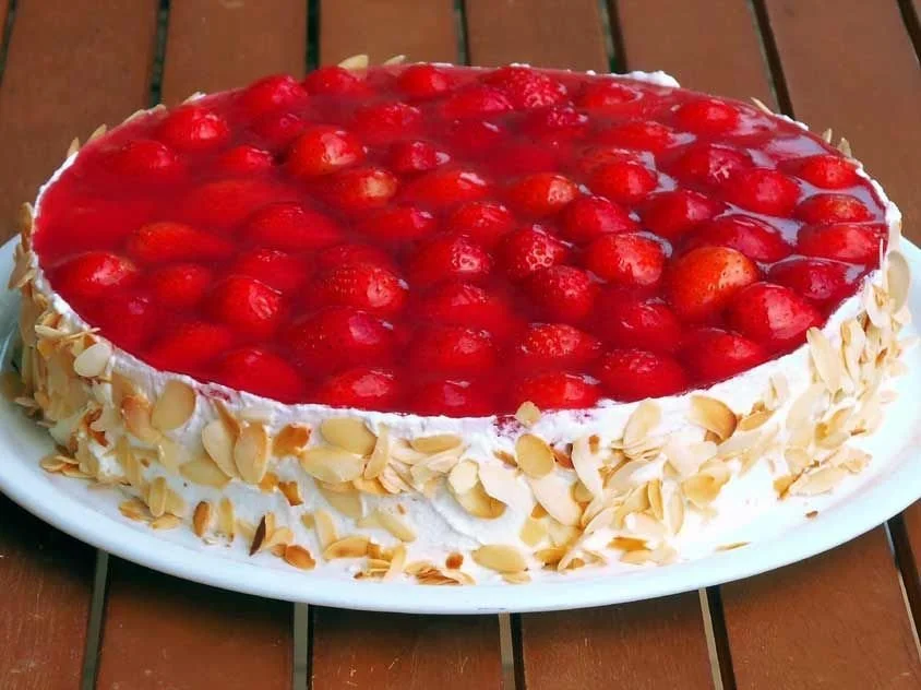 Leckerer Erdbeerkuchen auf einem Teller, dekoriert mit frischen Erdbeeren und Sahne.
