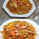 Teller mit gebratenen Nudeln, gemischtem Gemüse und einem Hauch von Sojasauce