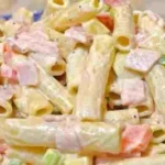 Nudelsalat mit Schinken und Käse auf einem Teller serviert.