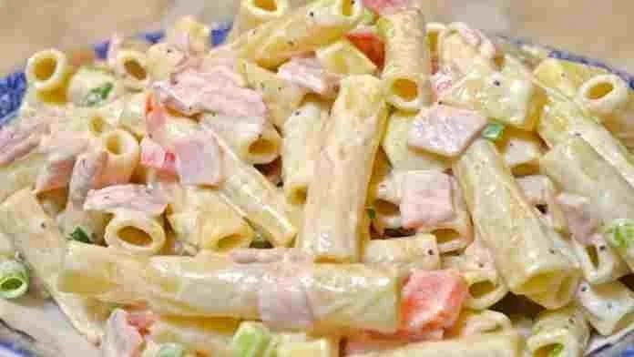 Nudelsalat mit Schinken und Käse auf einem Teller serviert.