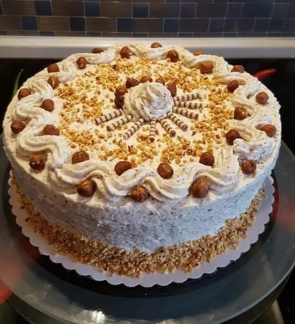 Sahne-Nuss-Torte mit frischer Sahne und Nüssen auf einem eleganten Teller.