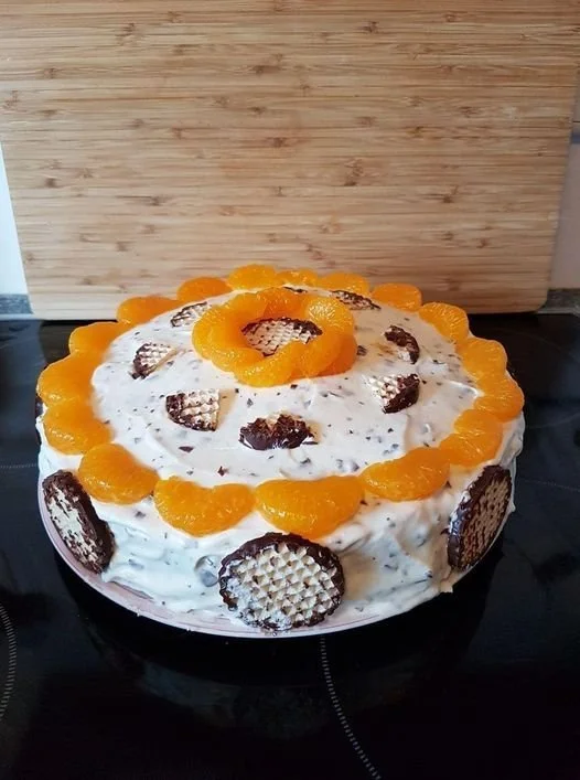 Delicious Schokokuss-Mandarinen Torte decorated with chocolate and mandarin slices.