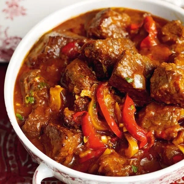 Schüssel mit traditionellem ungarischem Gulasch, garniert mit frischen Kräutern